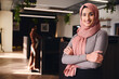 © Southworks - Portrait of confident young Middle Eastern woman smiling and looking at camera in coworking space