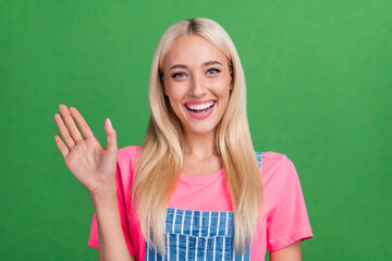 Canvas Print - Photo of friendly cheerful charming lady wave hand greeting friend wear striped overall isolated green color background