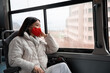 © Milles Studio/Stocksy - Thoughtful Asian woman in mask looking out bus window