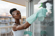 © Milles Studio/Stocksy - African housekeeper washing window with spray bottle