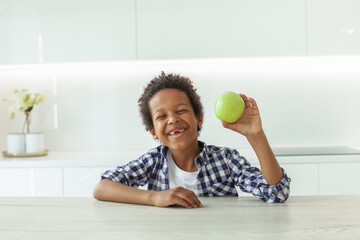 Laughing child boy with apple fruit indoor