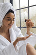 © Anna Tabakova/Stocksy - Woman using serum droplet in bathroom