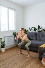 Sportive Woman Practicing Squat At Home