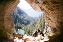 Travelers Admiring Forest And Mountains From Cave