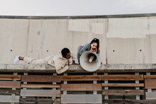 Woman Talking On Megaphone On Top Of Wall