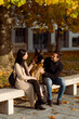 © Mauro Grigollo/Stocksy - Couple sitting on a bench with a dog