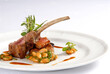 Roast rack of lamb or rack of beef accompanied by beans, served on a white plate on a white background with room for text. close up view
