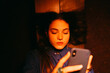 © Eloisa Ramos/Stocksy - Young woman using phone at night