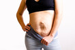 cropped woman dressed in black top and blue jeans. Diastasis and umbilical hernia after pregnancy