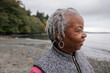 © Rob and Julia Campbell/Stocksy - Laughing older woman outside at the beach in fall.