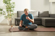 © Leire Cavia/Stocksy - Young man at home, doing yoga laughing