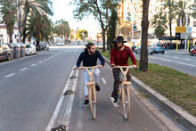Cheerful Friends Riding Wooden Bicycles On Road