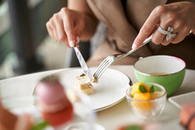 Woman Eating Dessert Using Fork And Knife In Restaurant