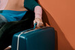 © Juan Moyano/Stocksy - young man grabs the handle of a blue retro suitcase