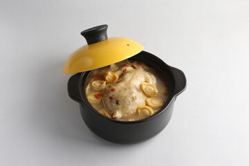 freshly hot stewed whole kampong chicken with abalone seafood in clay pot herbal soup on white background