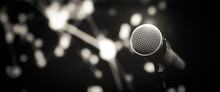 Microphone Public Speaking Background, Close Up Microphone On Stand For Speaker Speech Presentation Stage Performance With Blur And Bokeh Light Background.