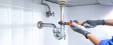Technician Plumber Using A Wrench To Repair A Water Pipe Under The Sink. Concept Of Maintenance, Fix Water Plumbing Leaks, Replace The Kitchen Sink Drain, Cleaning Clogged Pipes Is Dirty Or Rusty.