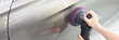 Mechanic polishing door of car with grinder closeup