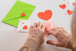DIY valentine's day card. Senior woman hands are closing an envelope