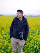 © zirong - A boy in a black down jacket stands in a field of rape flowers
