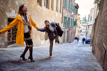 Wall Mural - A young elegant couple is having fun while walking in the city. Walk, rain, city, relationship