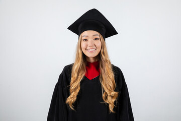 Smiling graduate student in mortarboard and bachelor gown on white background