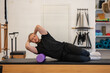 © lara-sh - Male fitness Pilates trainer shows exercises on special simulators. Pilates Stretch Tables. High quality photo