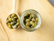 Capers in a glass jar. Pickled capers in a jar on a wooden board top view