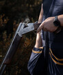 A man is about to reload while some smoking is coming out of his shotgun during a skeet shooting competition. Close up.