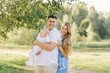 © Sunshine - A European family in the park on a summer day. Happy and smiling mom, dad and little son in their arms. Dad plus size