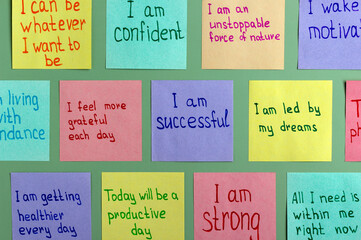 Positive affirmations for every day - words on multi-colored sheets for notes on a green background. Motivational concept with handwritten text.