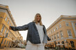 © Look! - Mischievous young caucasian woman wears white sweatshirt, denim jacket in summer or autumn. Blonde girl stands in front of camera outdoors. Trendy background with copy space.