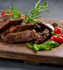 Wall Mural - roasted piece of beef ribeye cut into pieces on a vintage brown chopping board. Well done