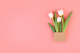 Fototapeta Tulipany - bouquet of white tulips in a craft envelope. surprise concept. isolated on pastel pink background. Object for design to women's day, mother's day, anniversary, valentine day. Minimalism concept