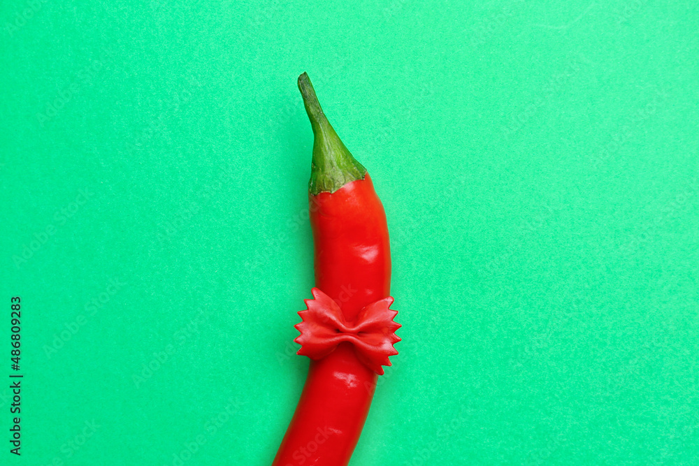 Hot chili pepper and pasta on green background