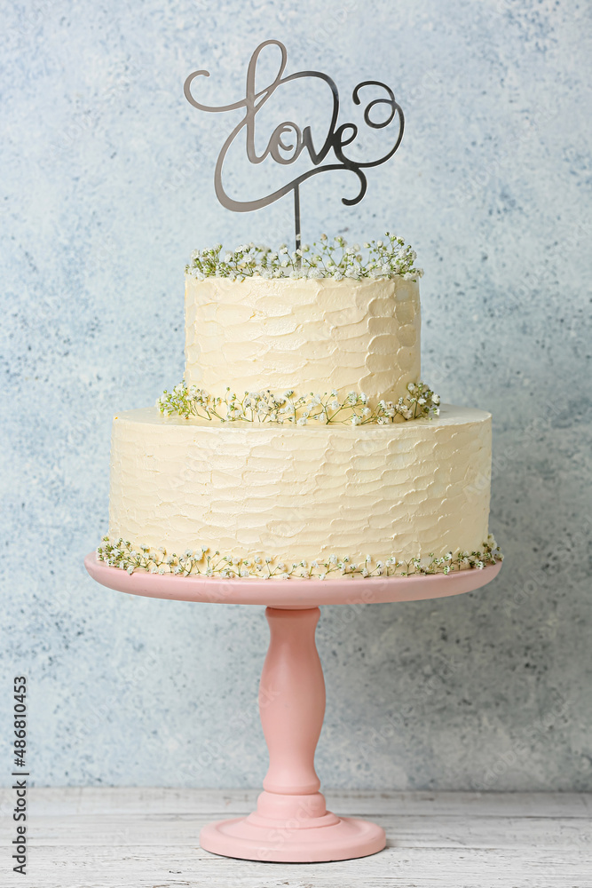 Dessert stand with beautiful wedding cake and topper with word LOVE on table