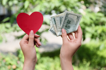 Wall Mural - Woman holding red paper heart and money outdoors, closeup. Donation concept