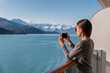 © Maridav - Alaska cruise ship passenger photographing amazing landscape entering Glacier Bay National Park, USA. Woman tourist taking photo picture using mobile cell smart phone on travel vacation