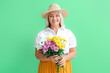 © Pixel-Shot - Mature woman holding bouquet of beautiful flowers on green background. International Women's Day celebration