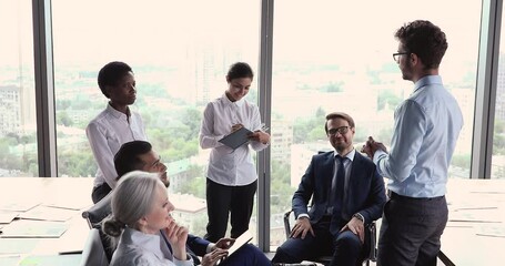 Poster - Young man psychologist coach lead motivation training seminar in diverse business people group. Multiracial corporate staff of different age gender engaged in teambuilding activity at office workplace