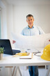 © epiximages - Architect with blue shirt is standing at height adjustable work table and is working