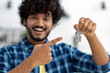 © kucherav - New life. Indian young man feels very ecstatic about their recent purchase of a new home or rented apartment. Satisfied homeowner. Male points his finger at the keys to his new home