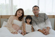 © plo - Portrait of Asian Pregnant Family Including Mother Father and Daughter Sitting Toghter on Bed