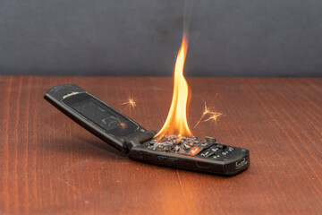 Old mobile phone burns with fire, battery fire.  The cause of the fire in the apartment, short circuit, old equipment.