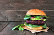 Vegetarian beet burger with avocado and spinach against a rustic dark wood background