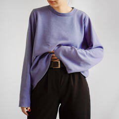 Wall Mural - Young woman wearing pastel purple crop sweater and black trousers isolated on white background.