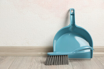 Poster - Plastic whisk broom with dustpan near light wall indoors. Space for text