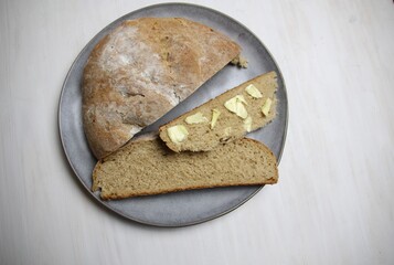 Sticker - Fresh baked rye  bread loaf and slice with butter on gray plate on white background