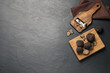 Wooden shaver with whole and sliced truffles on black table, flat lay. Space for text