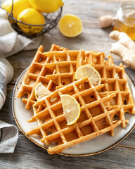 Wall Mural - Ginger lemon waffles with honey in a ceramic plate on a light gray wooden culinary background. Delicious healthy homemade cakes that increase immunity on the kitchen table	
